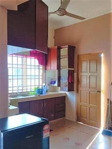 哥打巴鲁Nafili homestay 3bd 2br的厨房配有棕色橱柜和黑色冰箱