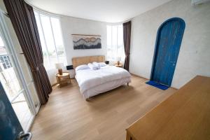万隆IMAH DHARMA的一间卧室配有一张带白色床单和蓝色窗帘的床。