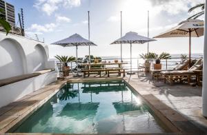 开普敦普利米大海城堡酒店的一座带桌子和遮阳伞的建筑屋顶游泳池