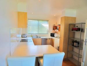 科夫斯港阿夸露娜海景度假屋的厨房配有白色的柜台和白色的椅子