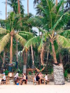 额布里Oliver`s Laguna ECO Lodge Hotel的坐在棕榈树海滩上桌子上的人