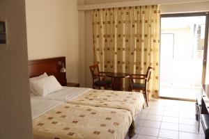 纳弗帕克托斯LEPANTO BEACH HOTEL的一间卧室配有一张床、一张桌子和一个窗户。