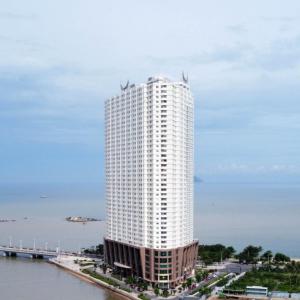 芽庄Phi Yen Muong Thanh 04 Apartment的水边高大的白色建筑