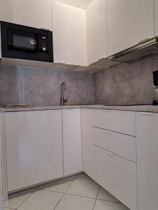 特罗吉尔Apartmani Beba的厨房配有白色橱柜和微波炉