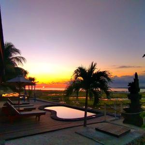 蓝梦岛Double'A beach house的日落时分,在拥有游泳池和棕榈树的度假村