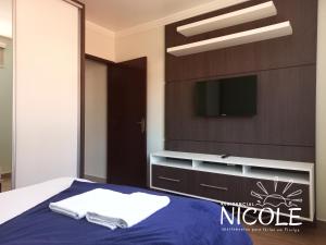 弗洛里亚诺波利斯Residencial Nicole的卧室配有一张床铺,墙上配有电视