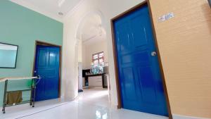 哥打巴鲁PCB民宿的走廊上的两扇蓝色门,配有桌子