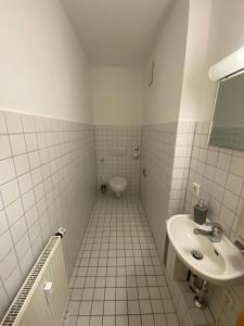 尼尔廷根Wohnung in Nürtingen的白色瓷砖浴室设有水槽和卫生间