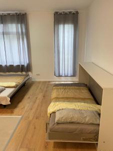 尼尔廷根Wohnung in Nürtingen的客房内设有两张床,铺有木地板,设有窗户。