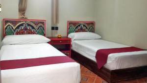 丹吉尔马兰汽车旅馆的一间设有两张床和一张红色桌子的房间