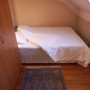 ProkupljeLoli Caffe Apartment的一间小卧室,配有一张带白色床单和地毯的床