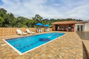 林多亚Casa São Luis的房屋旁的游泳池配有椅子和遮阳伞