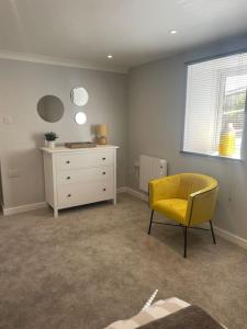 雷德鲁斯Sunny Corner - lovely 2 bedroom appt的一间设有黄色椅子和梳妆台的房间