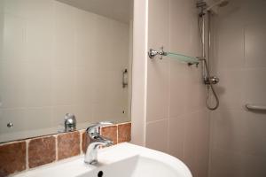 温奇尔西Winchelsea Lodge的浴室配有盥洗盆和带镜子的淋浴
