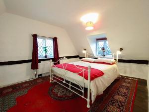斯托马基特Laburnham Cottage的一间卧室配有一张床和红色地毯