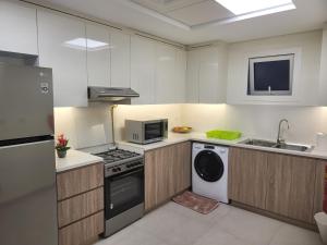 迪拜FULLY FURNISHED 2BR APARTMENT WITH MAIDS ROOM B411的厨房配有炉灶、洗衣机和烘干机