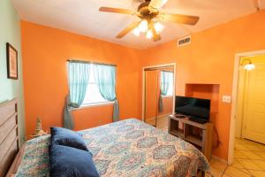 南帕诸岛South Padre Island condo is walking distance to the beach, Sleeps 6, Third Floor, 2024 Traveler Award的一间卧室设有橙色的墙壁、一张床和吊扇。