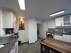 斯图加特Aparthotel Waldhorn Wohnung Allgäustyle的厨房配有白色橱柜和桌子