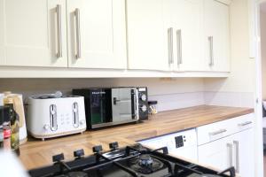 Great SankeyBee Stays - Maliston House的厨房配有白色橱柜、炉灶和微波炉。