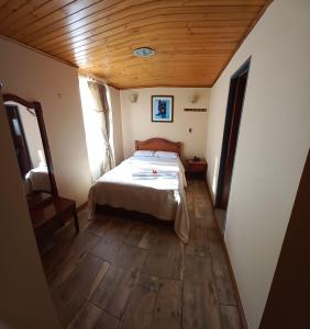 帕斯托Hotel Buenaventura的一间卧室设有一张床和木制天花板