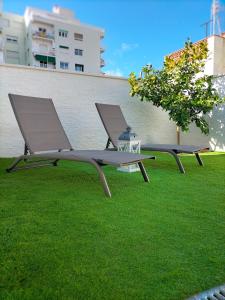布拉内斯Casa junto al mar的两把长椅坐在一栋楼的草地上