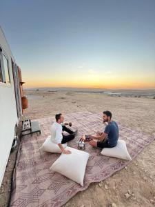 耶鲁姆קסיופאה חוויה במדבר的两个男人坐在海滩上一条毯子上