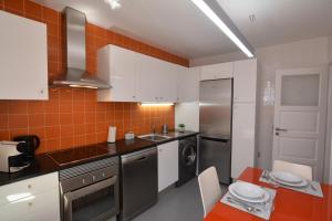辛特拉Casa da Fonte的厨房配有白色橱柜和橙色瓷砖墙