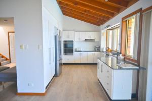 GorokanLakeside Luxury的厨房配有白色橱柜和木制天花板