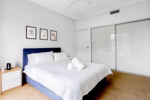 布里斯班G3 Apartment的白色卧室设有一张大床和一个玻璃门