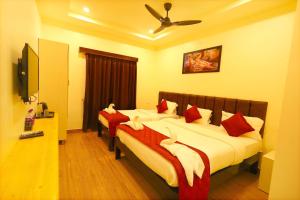 斯里卡拉哈斯蒂Hotel Vijaya Grand的一间卧室配有两张带红白色枕头的床