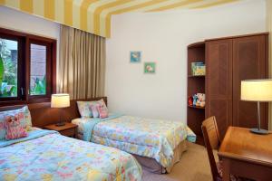 瑟古邦巴特玛假日酒店的一间卧室配有两张床、一张桌子和一张书桌