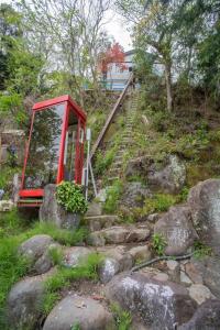热海ゴンドラヴィラ イン熱海的山丘上的一个红色电话亭,上面有岩石