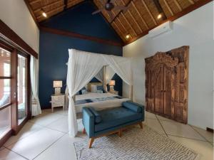 塞米亚克Beautiful Villa Indah的一间卧室配有天蓬床和蓝色的沙发