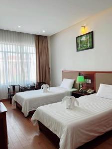 河静Bình Minh Hotel的酒店客房设有两张床和一张桌子。