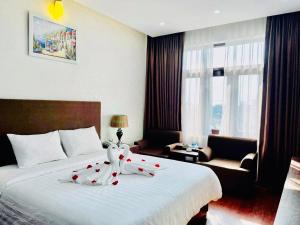 河静Bình Minh Hotel的酒店客房的床铺上摆放着红色玫瑰花
