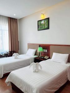 河静Bình Minh Hotel的酒店客房,配有两张带白色床单的床