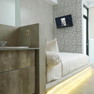 雅加达DParagon Jakarta Timur的卧室配有白色的床和砖墙