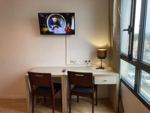 阿维尼翁Appart'Hotel - Gare TGV - Courtine - Confluence - 218的客房设有一张桌子、两把椅子和一台墙上的电视