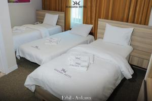 埃尔比勒Niagara Hotel Erbil的酒店客房内的三张床,配有白色床单