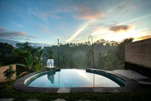 德格拉朗Campuhan Sebatu Resort的花园内的游泳池,背景是日落