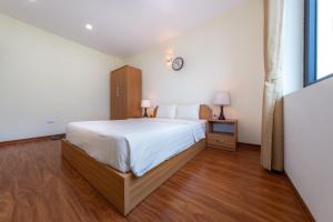 河内Granda Quan Hoa Apartment的卧室配有一张床,墙上挂着一个钟