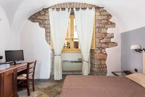 博萨Locanda di Corte的一间卧室配有一张床、一张书桌和一个窗户。