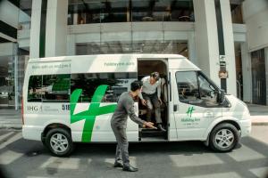 胡志明市Holiday Inn & Suites Saigon Airport, an IHG Hotel的两个人站在一辆面包车的后面