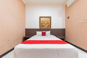 井里汶RedDoorz near Kejaksan Station Cirebon的卧室配有一张大白色床和红色毯子