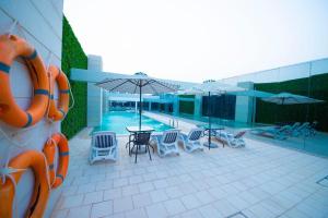 利雅德Sarwat Park Hotel Riyadh - Diplomatic Quarter的一个带桌椅和遮阳伞的游泳池