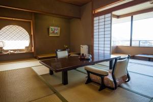 伊豆Sakahijiri gyokushoen的一间带木桌和椅子的用餐室