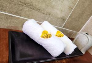 瓜拉丁加奴上城生态酒店 的黑色托盘上两条白色毛巾,上面有黄色的弓