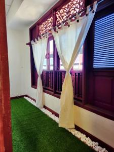 瓜拉丁加奴上城生态酒店 的客房铺有绿色地毯,设有窗帘和窗户。