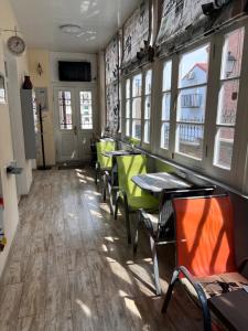 第比利斯Tbil Home Hostel的餐厅设有绿色的椅子和桌子以及窗户。