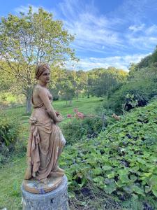 Vattetot-sur-MerLe Manoir by CauxCottes的站在花园中立柱上的女人的雕像